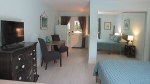 Una habitación de hotel con cama, escritorio, silla, televisor y ventilador de techo.
