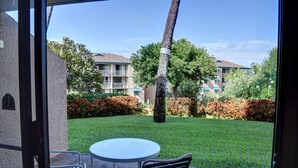 A patio with a round table and two chairs, a palm tree, and a view of apartment buildings.