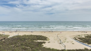 Een strand met een houten looppad naar de kust, zandstrand en zee.