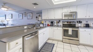 Een moderne keuken met witte kasten, roestvrijstalen apparatuur en een betegelde achterwand.