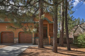 A two-story log cabin with a front porch, a staircase, and a garage.