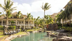 A resort with a pool, palm trees, and a multi-story building.