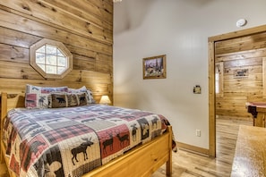 A wooden-paneled bedroom with a bed, a window, and a door.