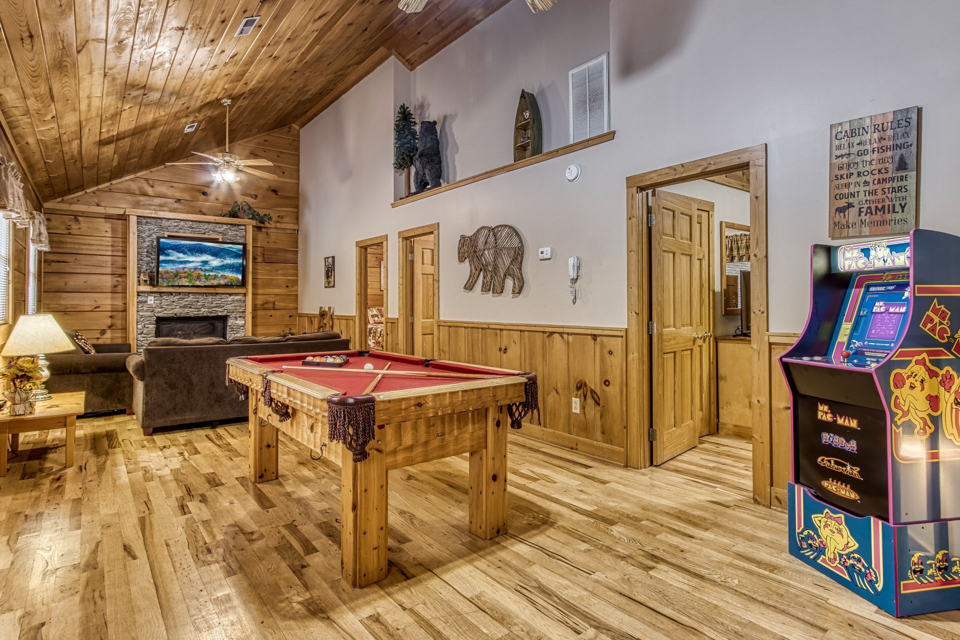 A cozy room with a pool table, a sofa, a fireplace, and a pinball machine.