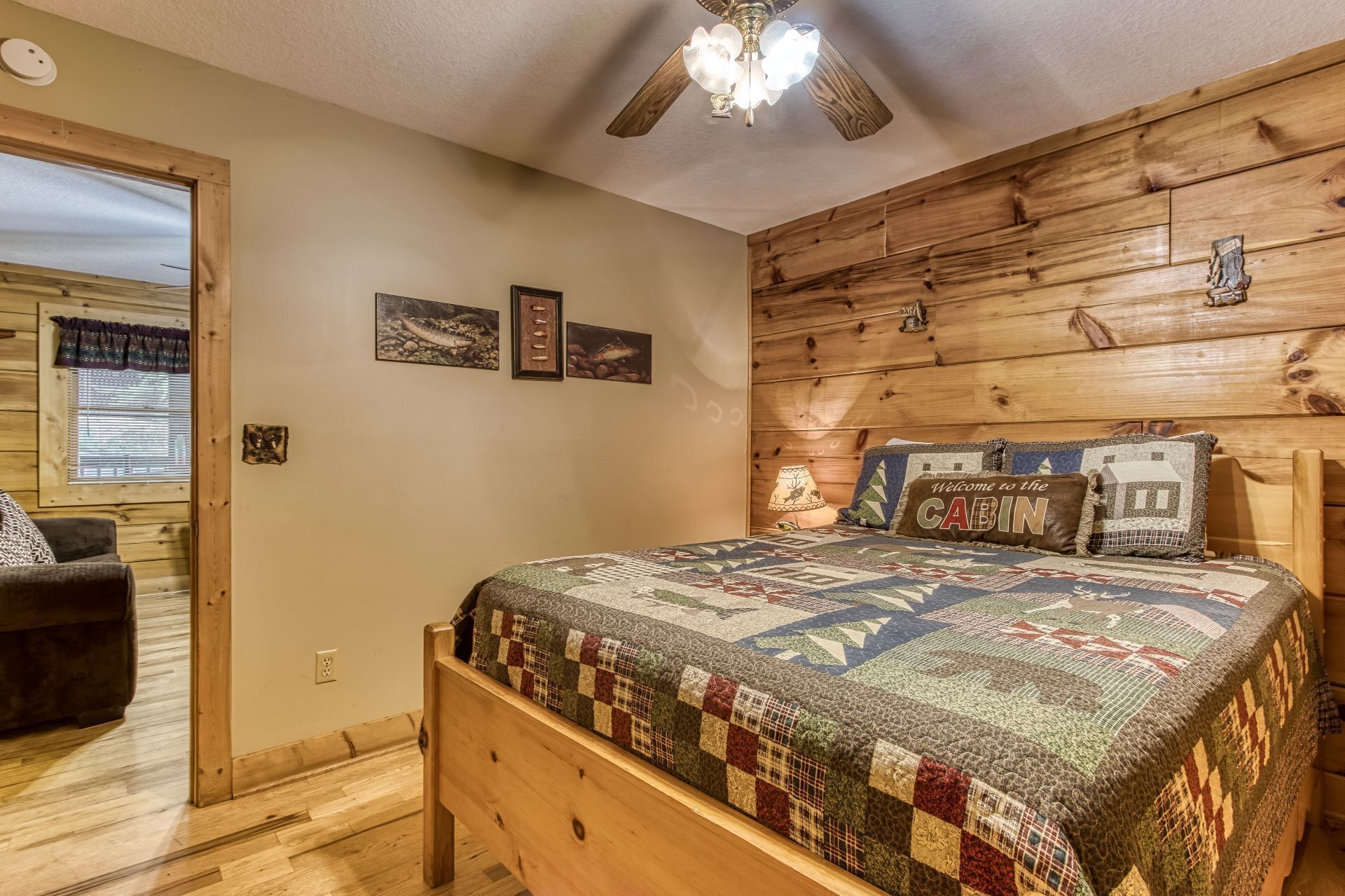 A cozy cabin-style room with a wooden headboard, a quilted bedspread, and a ceiling fan.