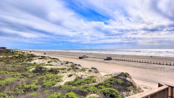 A beach with a wooden boardwalk, sandy dunes, and a clear sky.