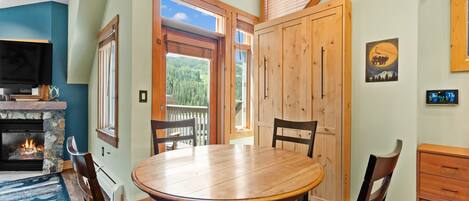 Un coin repas chaleureux avec une table ronde en bois, des chaises rembourrées et une cheminée.