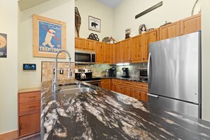 A modern kitchen with wooden cabinets, stainless steel appliances, and a marble countertop.