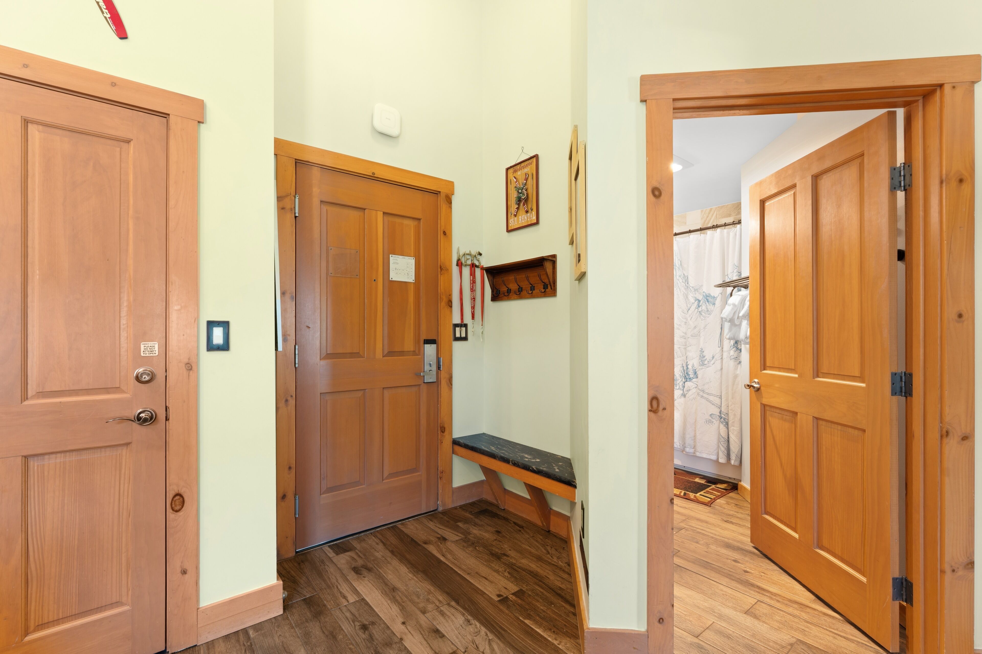 A hallway with wooden doors, a bench, and a ski rental sign.