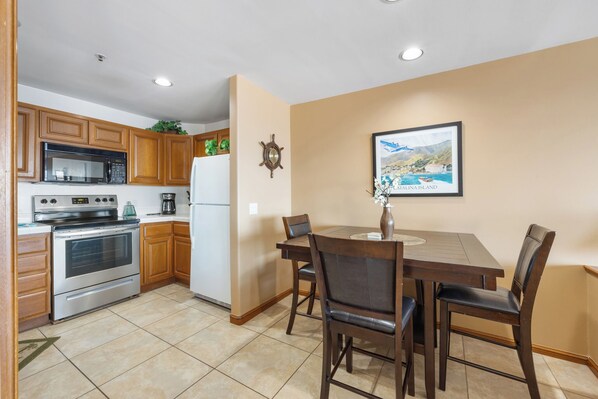 A kitchen with wooden cabinets, a microwave, an oven, and a dining table with chairs.