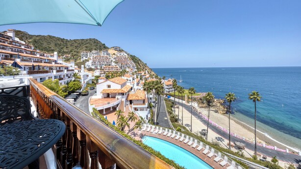 A coastal hotel with a pool, beach access, and a view of the sea.