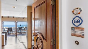 A wooden door leading to a balcony with a view of the ocean.