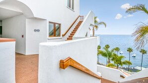 A modern building with a staircase leading to a balcony overlooking the sea.