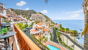 A coastal town with terraced buildings, a pool, and a view of the sea.