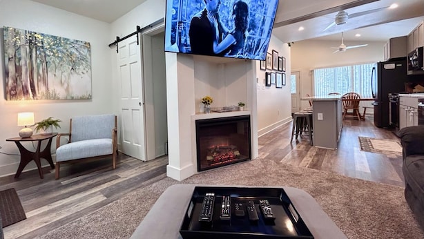 A modern living room with a fireplace, a flat-screen TV mounted above it, and a tray with remote controls.