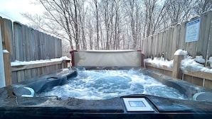 A hot tub with a wooden deck and a sign indicating hot tub safety rules.