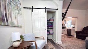 A cozy living room with a chair, a small table, and a sliding door leading to a storage area.