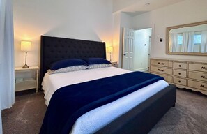 Une chambre à coucher avec un grand lit, deux tables de chevet, une commode et un miroir au mur.
