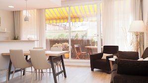 Un salon moderne avec un coin repas, de grandes portes-fenêtres coulissantes donnant sur un balcon et une vue sur l’extérieur.
