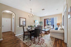 Relax in this open-plan living space featuring a dining area with a table for four and a cozy seating area with a sofa.