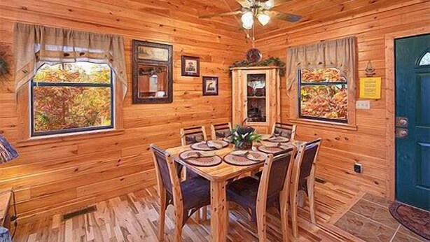 Interior de una cabaña de madera con una mesa de comedor dispuesta para seis personas, rodeada de sillas.