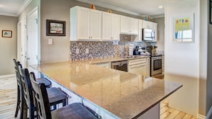 A kitchen with white cabinets, a granite countertop, and a tiled backsplash. - This wonderful condo is located on the 2nd floor of the beachfront building in f (Port Aransas)