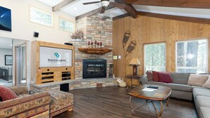 Un salón amplio con chimenea de piedra, vigas de madera y un ventanal grande.