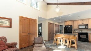 Un amplio espacio habitable con un gran puerta de madera, un sillón de cuero marrón y una mesa de comedor de madera con taburetes.