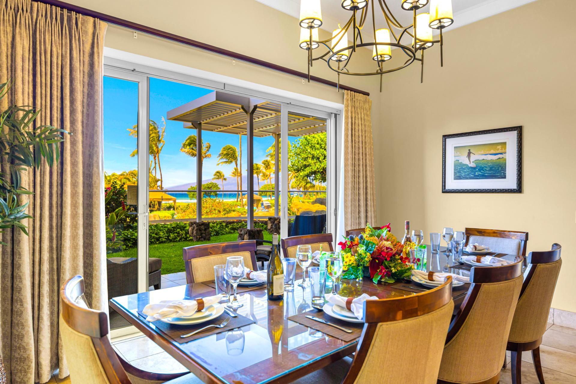Formal dining room at Honua Kai Hokulani 150 — seating for eight beneath a wrought-iron chandelier with a direct ocean view through the lanai doors