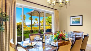 Formal dining room at Honua Kai Hokulani 150 — seating for eight beneath a wrought-iron chandelier with a direct ocean view through the lanai doors
