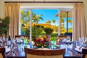 Dining room at Honua Kai HKH-150 — table for eight with a floral centerpiece beside garden-view sliding doors - Honua Kai | Ocean View (Partial) 3 BR | Free Car w/ 6+ Nights | HKH-150 (Lahaina)