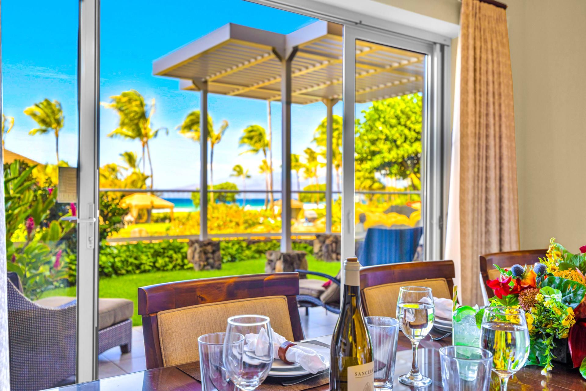 Oceanview dining at Honua Kai HKH-150 — private lanai table set with wine, framed by the pergola and Pacific horizon