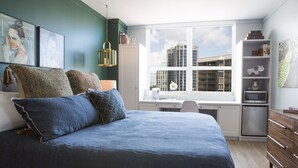 A bedroom with a bed, a desk, and a view of buildings through a large window. - Adorable 12th Floor Standard Unit-Parking Included (Miami)