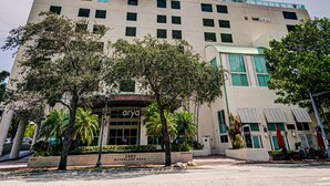 A high-rise hotel with a modern design, featuring multiple balconies and a prominent entrance with a sign. - Adorable 12th Floor Standard Unit-Parking Included (Miami)