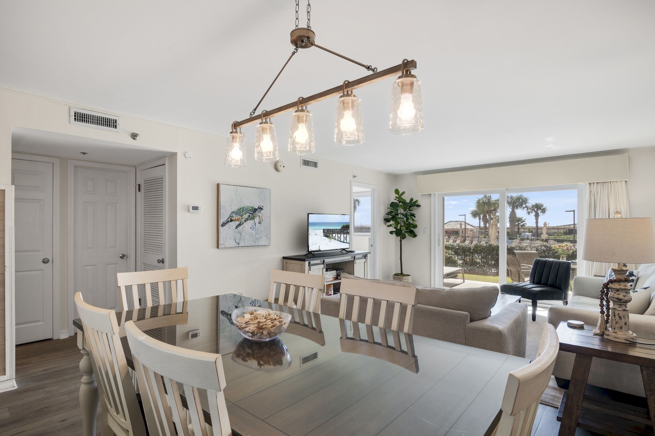 Uma sala de estar moderna com área de jantar, uma janela grande com vista e um lustre.
