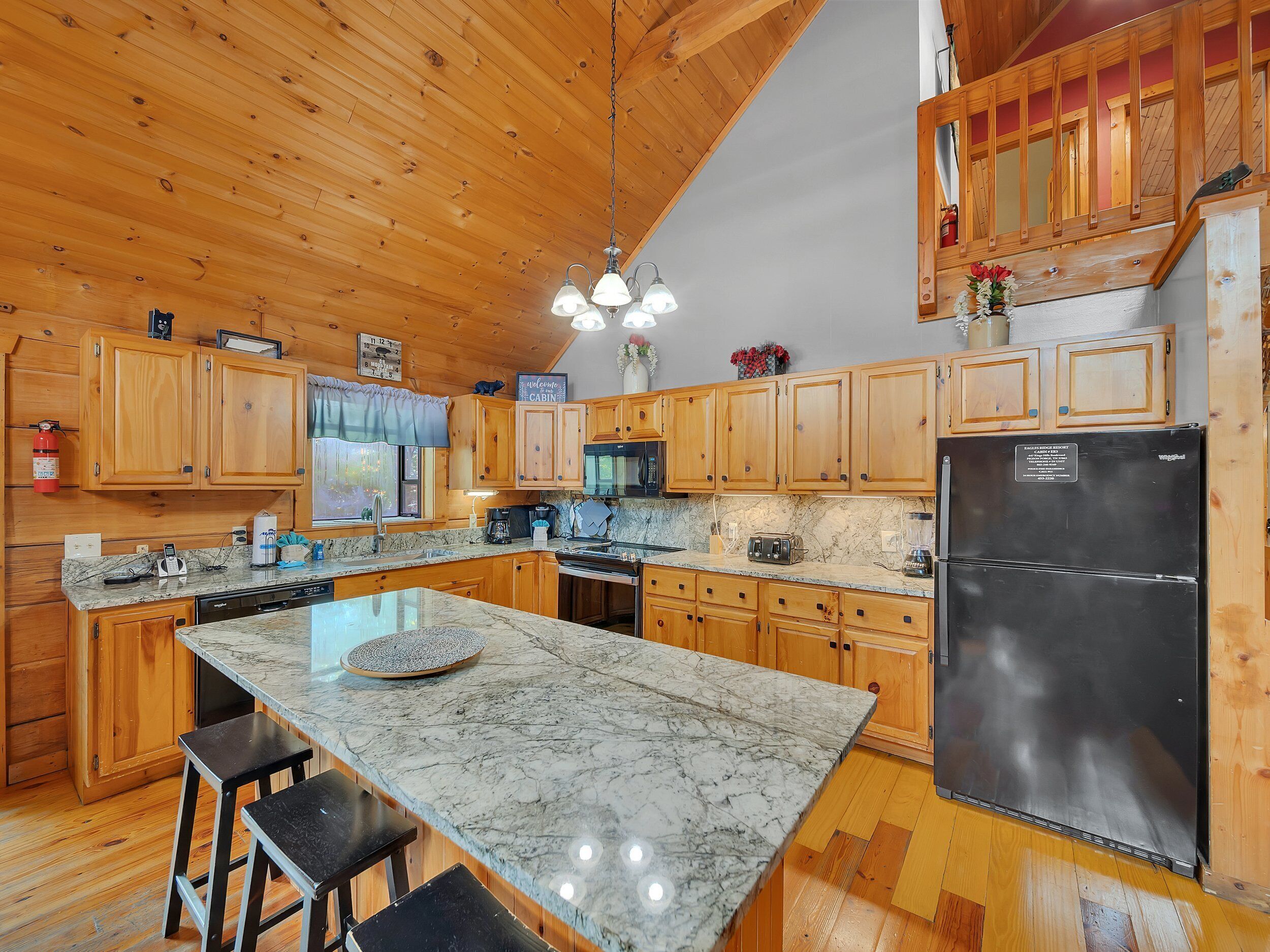 A spacious kitchen with wooden cabinets, a large island, and a stainless steel refrigerator.