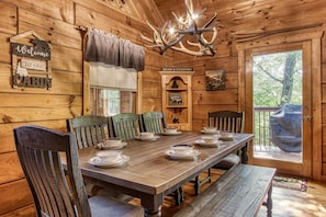 Cozy cabin interior with a dining table for four, a chandelier, and a rustic bench.