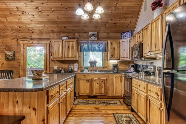 Enjoy cooking in this well-equipped kitchen with a central island, stainless steel appliances, and a window overlooking lush greenery.