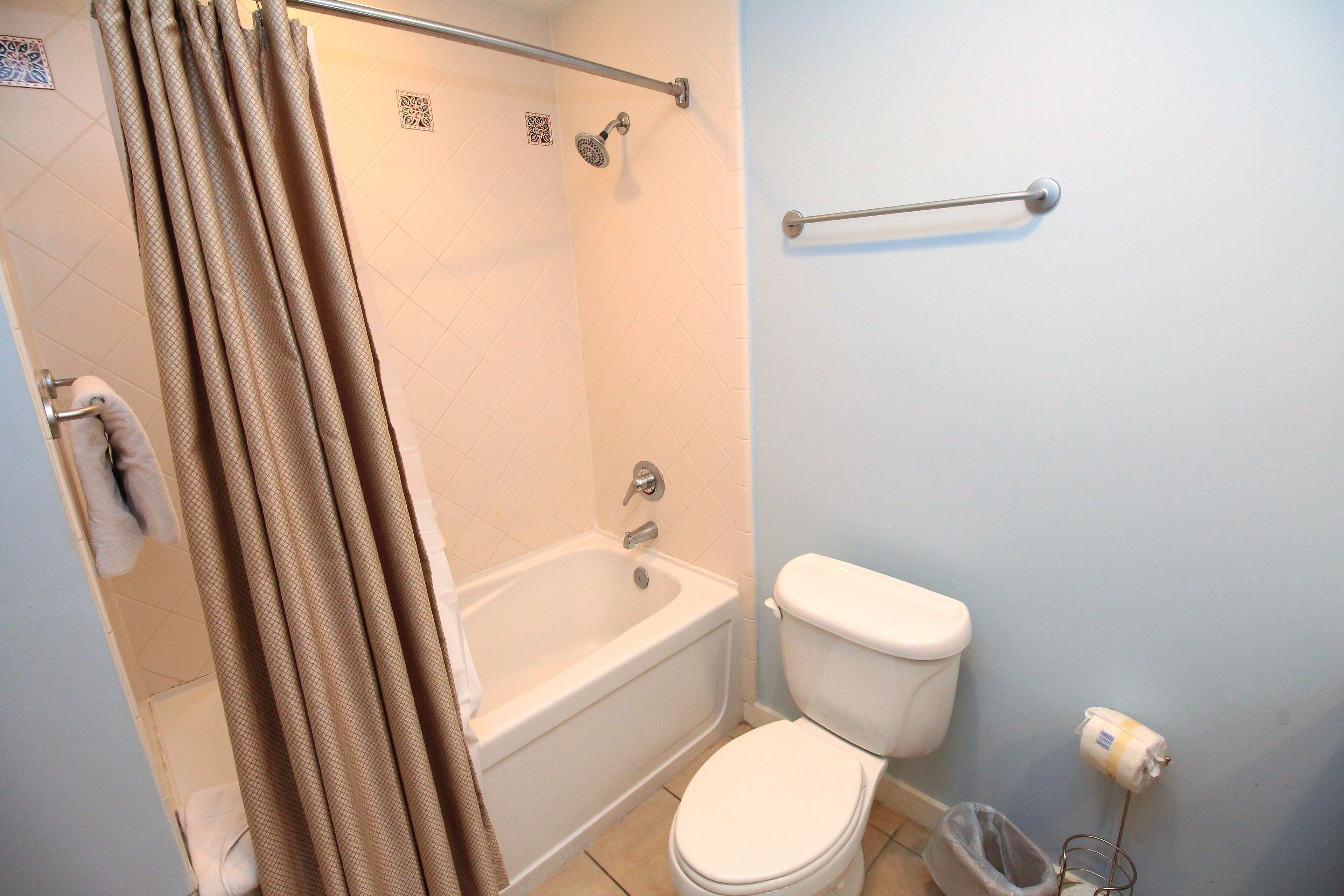 A bathroom with a bathtub, toilet, and shower curtain.