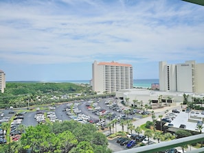 A hotel with a parking lot, a view of the ocean, and surrounding greenery.