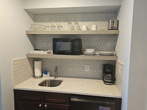 A compact kitchen with a microwave, coffee maker, and a sink.