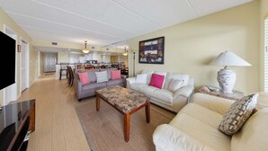 Ein Wohnzimmer mit zwei Sofas, einem Couchtisch, einem Fernseher und einem Essbereich mit Stühlen und einem Tisch.