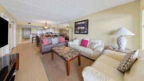 A living room with two sofas, a coffee table, a TV, and a dining area with chairs and a table. - Edgewater 104 Ground Floor! Pool Heated during Colder Months! (South Padre Island)