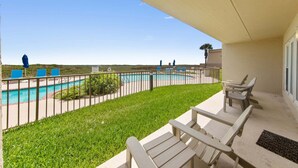Ein Balkon mit Blick auf einen Swimmingpool, eine Rasenfläche und einige Liegestühle.