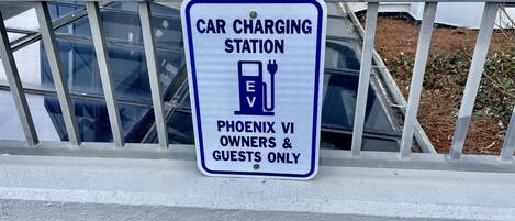 Un panneau indiquant une borne de recharge pour véhicules électriques, avec un symbole de prise et le texte précisant qu’elle est réservée aux propriétaires et aux invités de Phoenix VI.