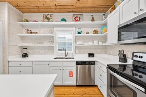 A modern kitchen with white cabinetry, a stainless steel dishwasher, and a black oven.