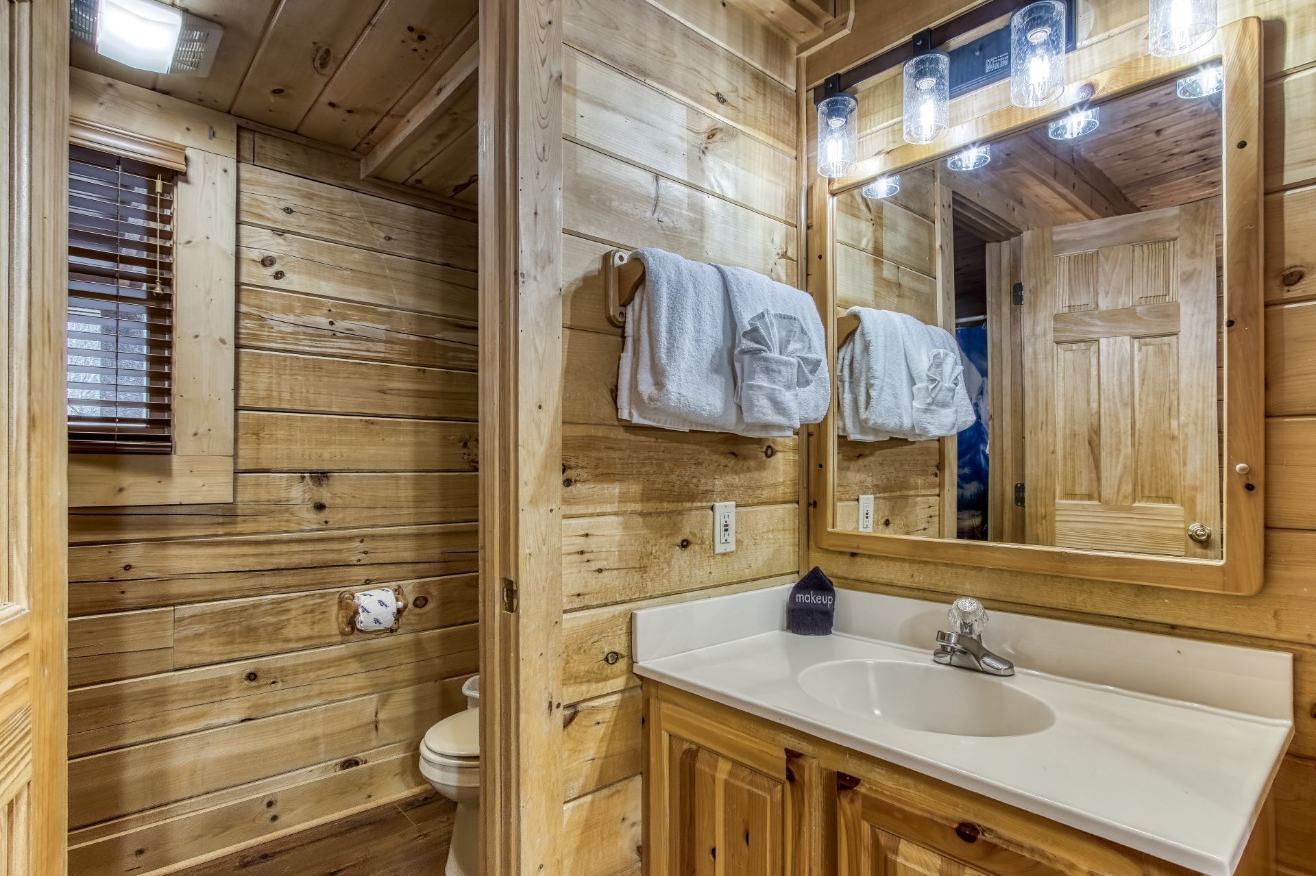 A wooden cabin bathroom with a sink, mirror, and towels.