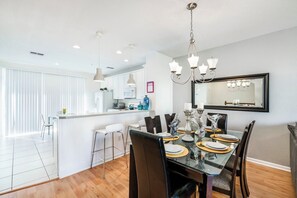 A modern dining area with a glass table, black chairs, and a chandelier.