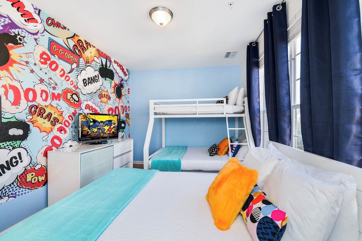 A bedroom with bunk beds, a desk, and a wall with comic book-style wallpaper.