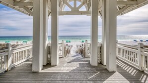 Eine hölzerne Mole, die zu einem Strand mit einer weißen Laube führt.